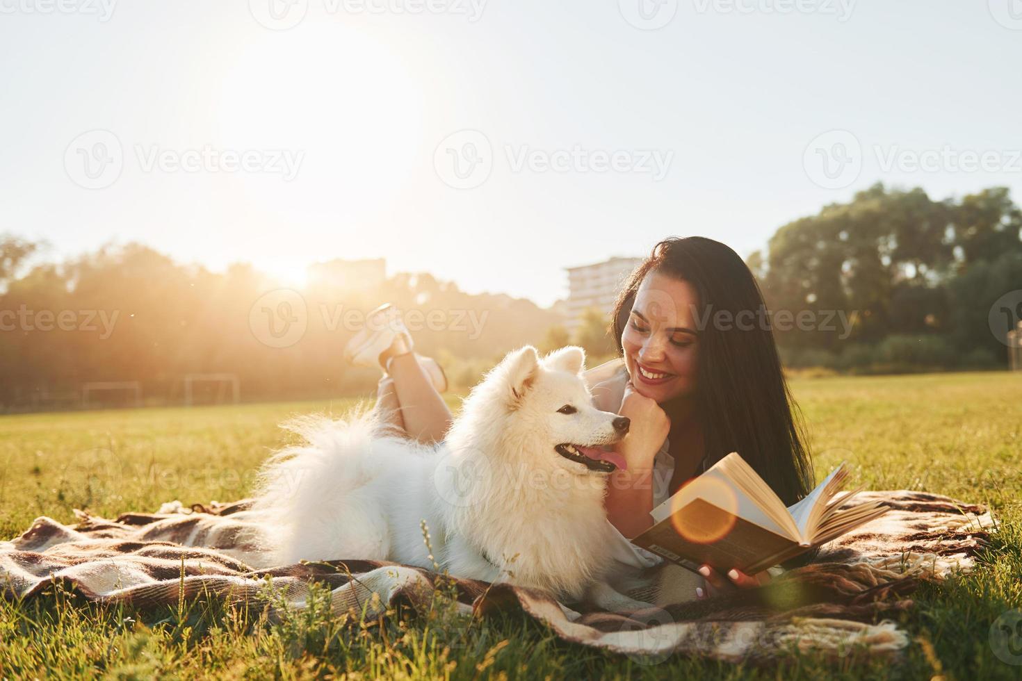 Warm weather. Woman with her dog is having fun on the field at sunny daytime photo