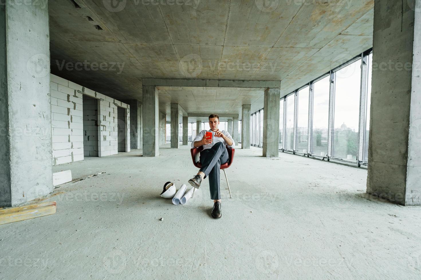 Successful young man in formal wear is working indoors on the construction photo