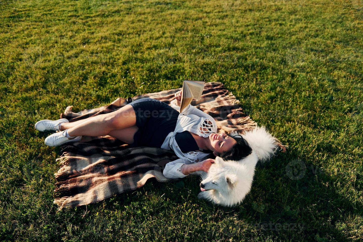 Top view. Woman with her dog is having fun on the field at sunny daytime photo