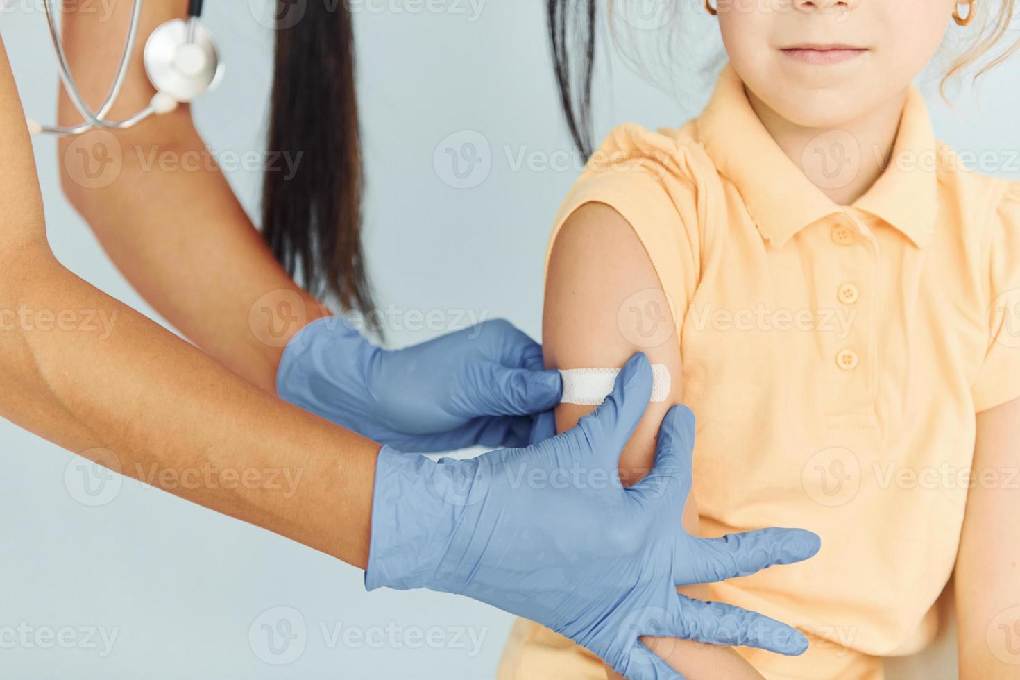 Doctor in uniform making vaccination to the little girl photo