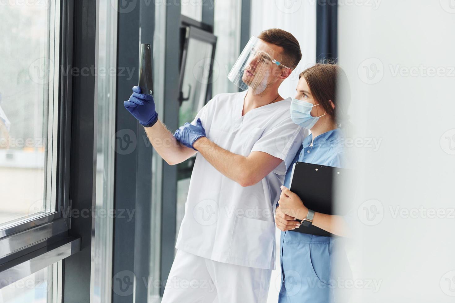 Looking at documents. Two doctors in uniform standing indoors and working together photo