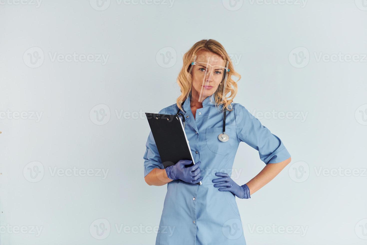 Wearing protective mask. Young female doctor in uniform is indoors photo