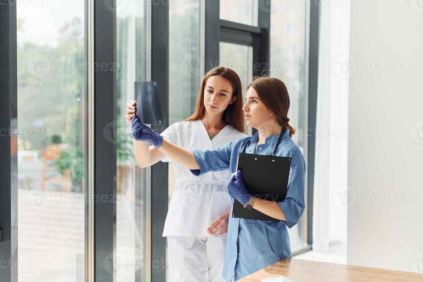 Two doctors in uniform standing indoors and working together photo