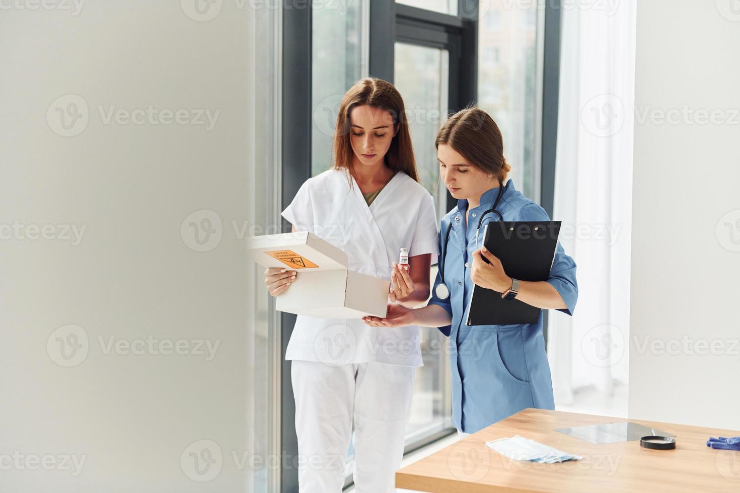 Looking at documents. Two doctors in uniform standing indoors and working together photo