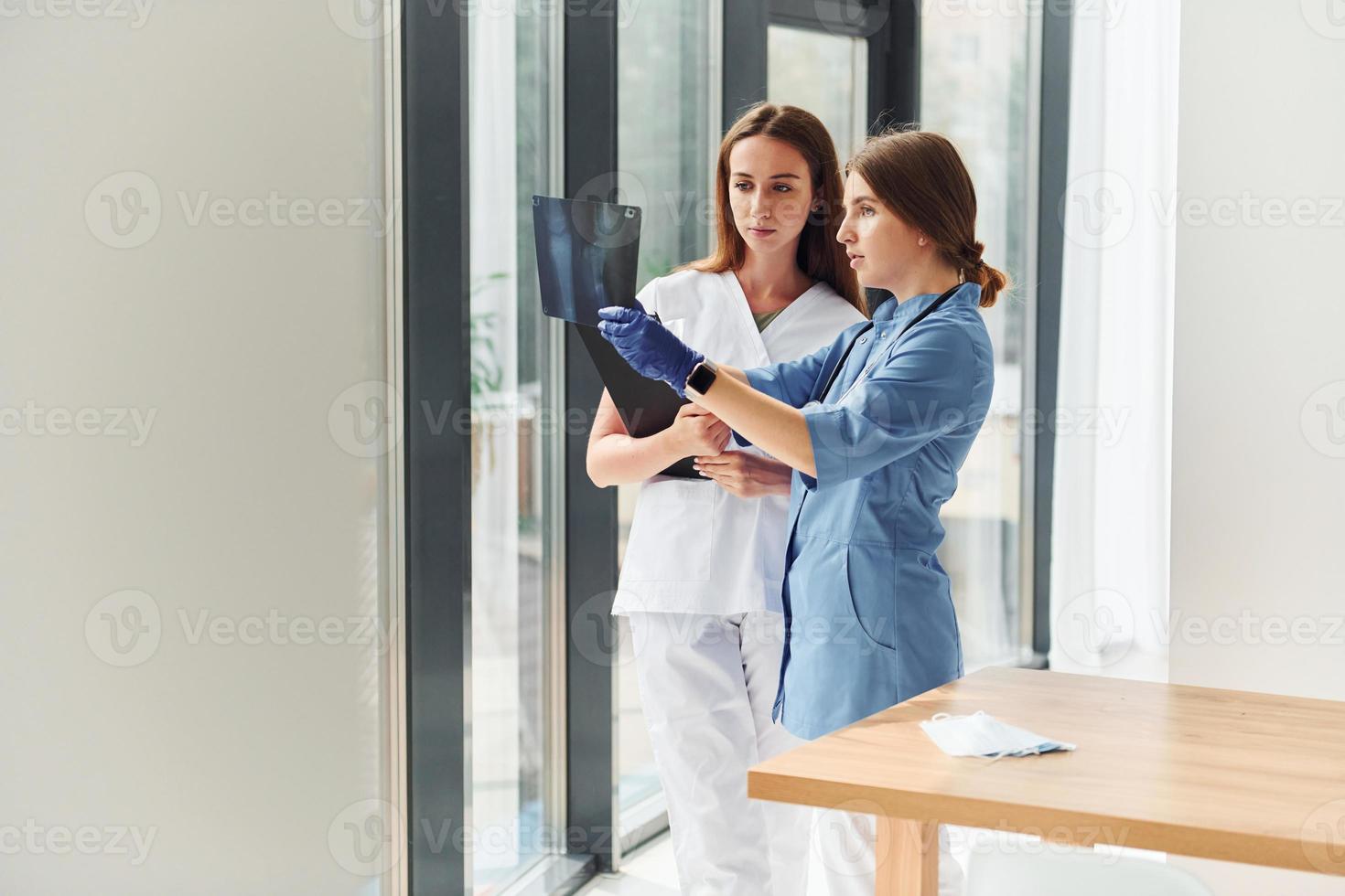 With documents. Two doctors in uniform standing indoors and working together photo