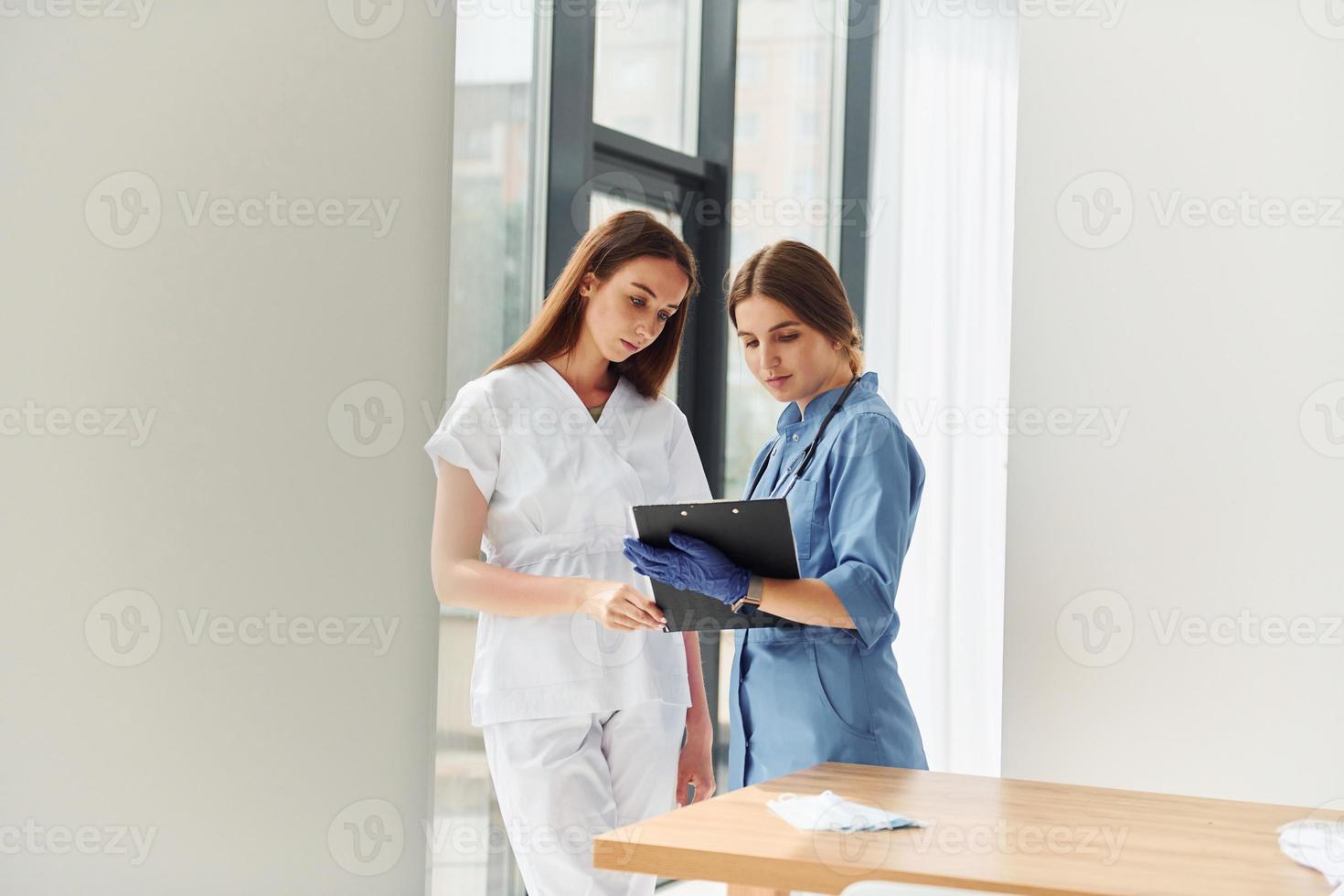 Two doctors in uniform standing indoors and working together photo
