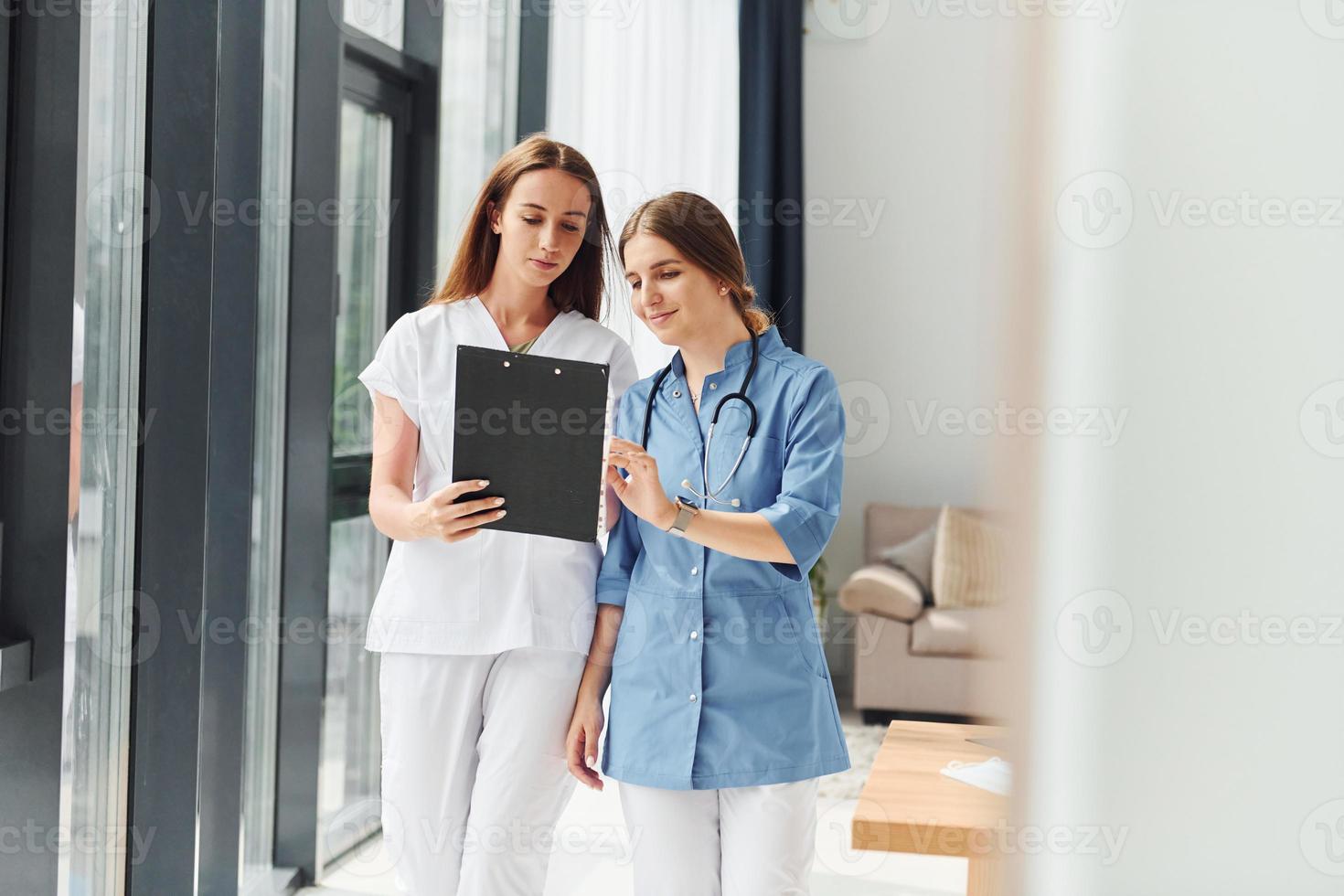 With documents. Two doctors in uniform standing indoors and working together photo