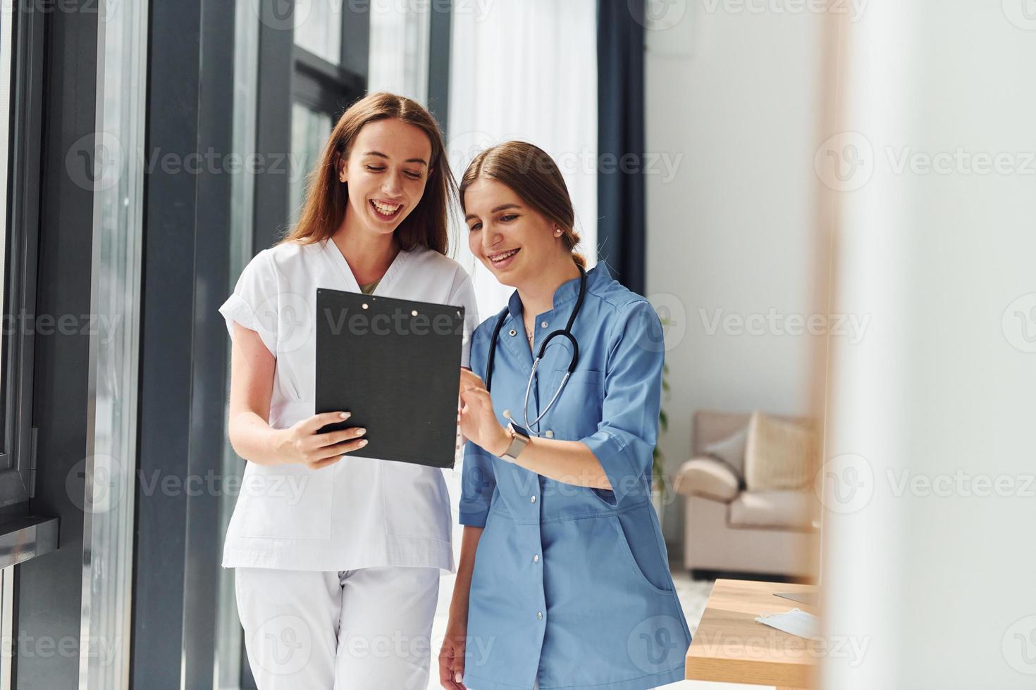 With documents. Two doctors in uniform standing indoors and working together photo