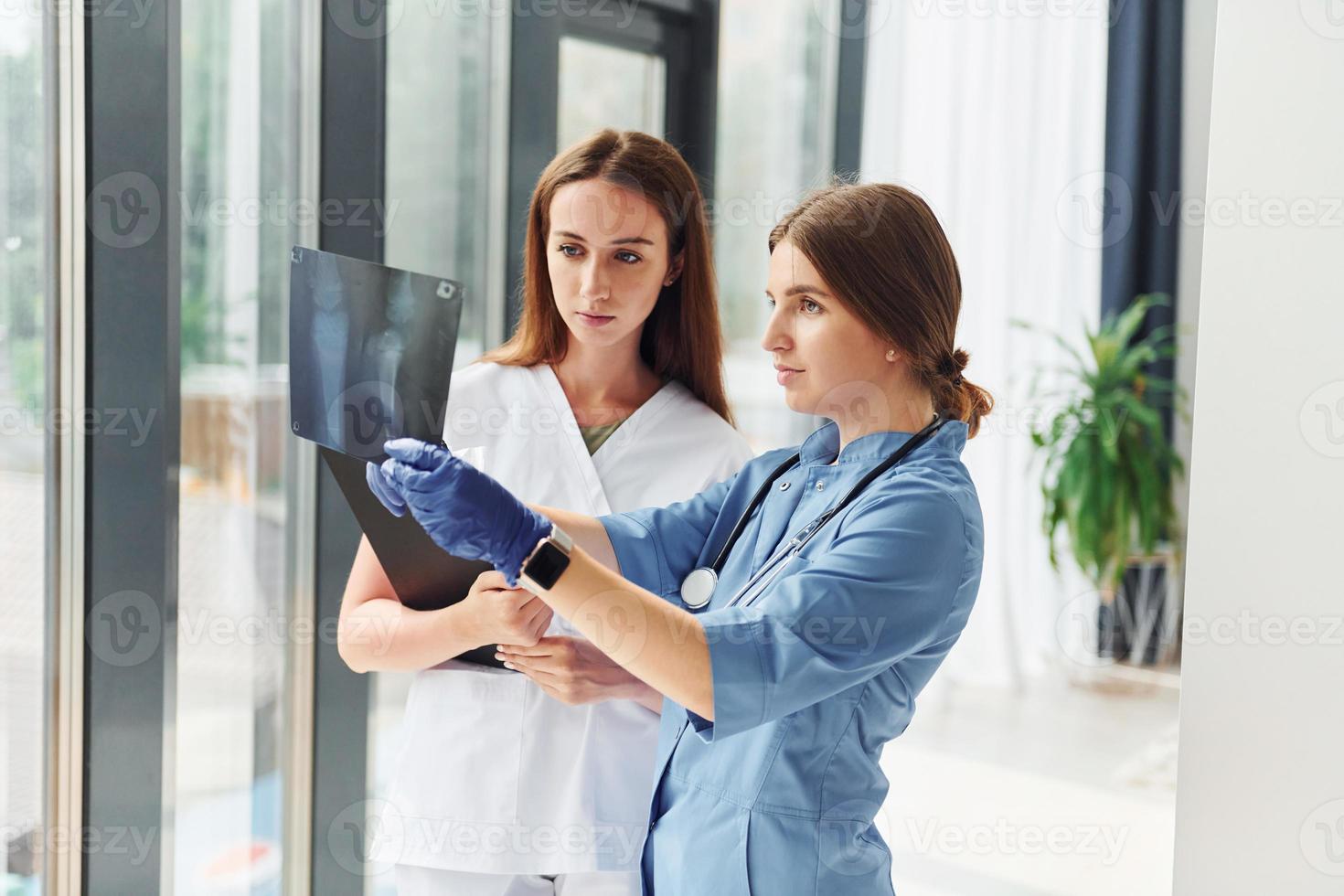 With documents. Two doctors in uniform standing indoors and working together photo