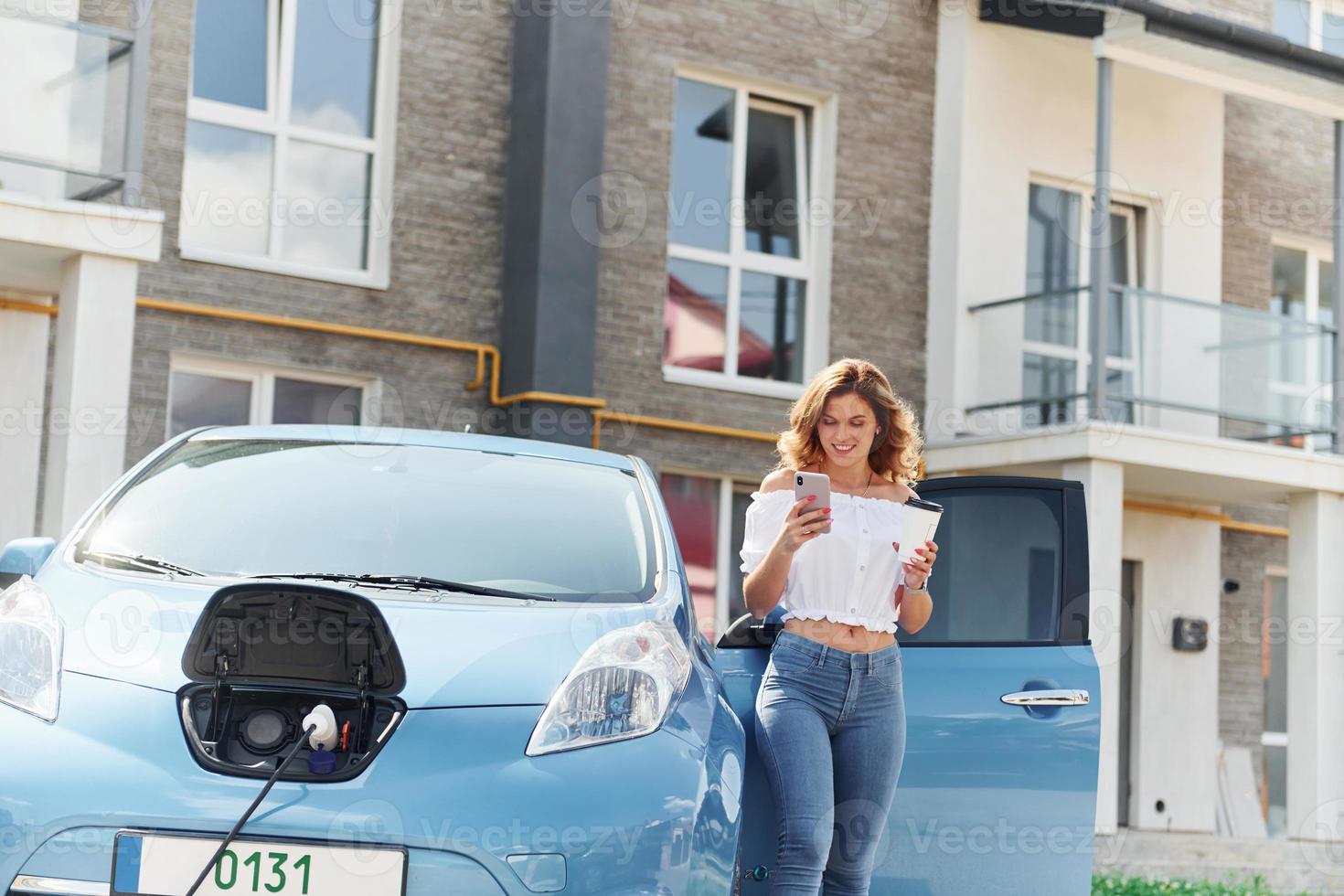 Using phone. Young woman in casual clothes with her electromobile outdoors at daytime photo