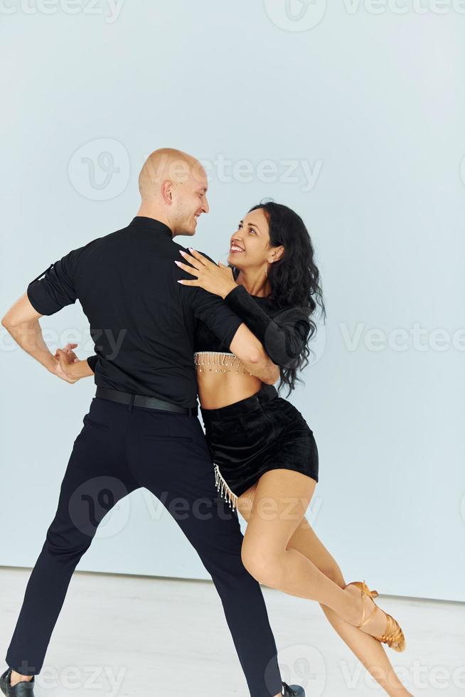 Dancing in the studio with white background. Cheerful couple is together indoors photo