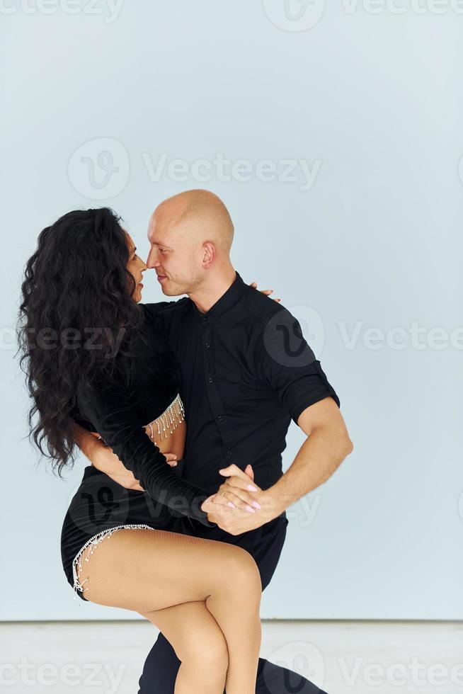 Dancing in the studio with white background. Cheerful couple is together indoors photo