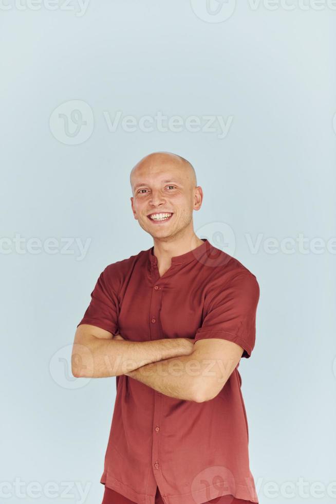 con los brazos cruzados. el hombre con camisa casual roja está de pie contra el fondo blanco foto