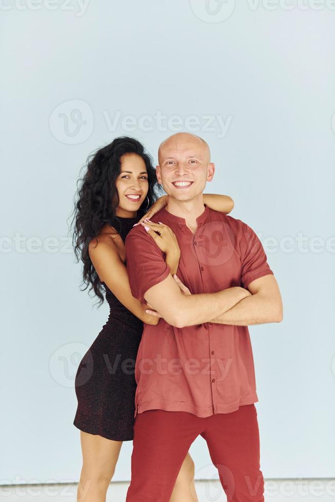 Standing in the studio against white background. Cheerful couple is together indoors photo