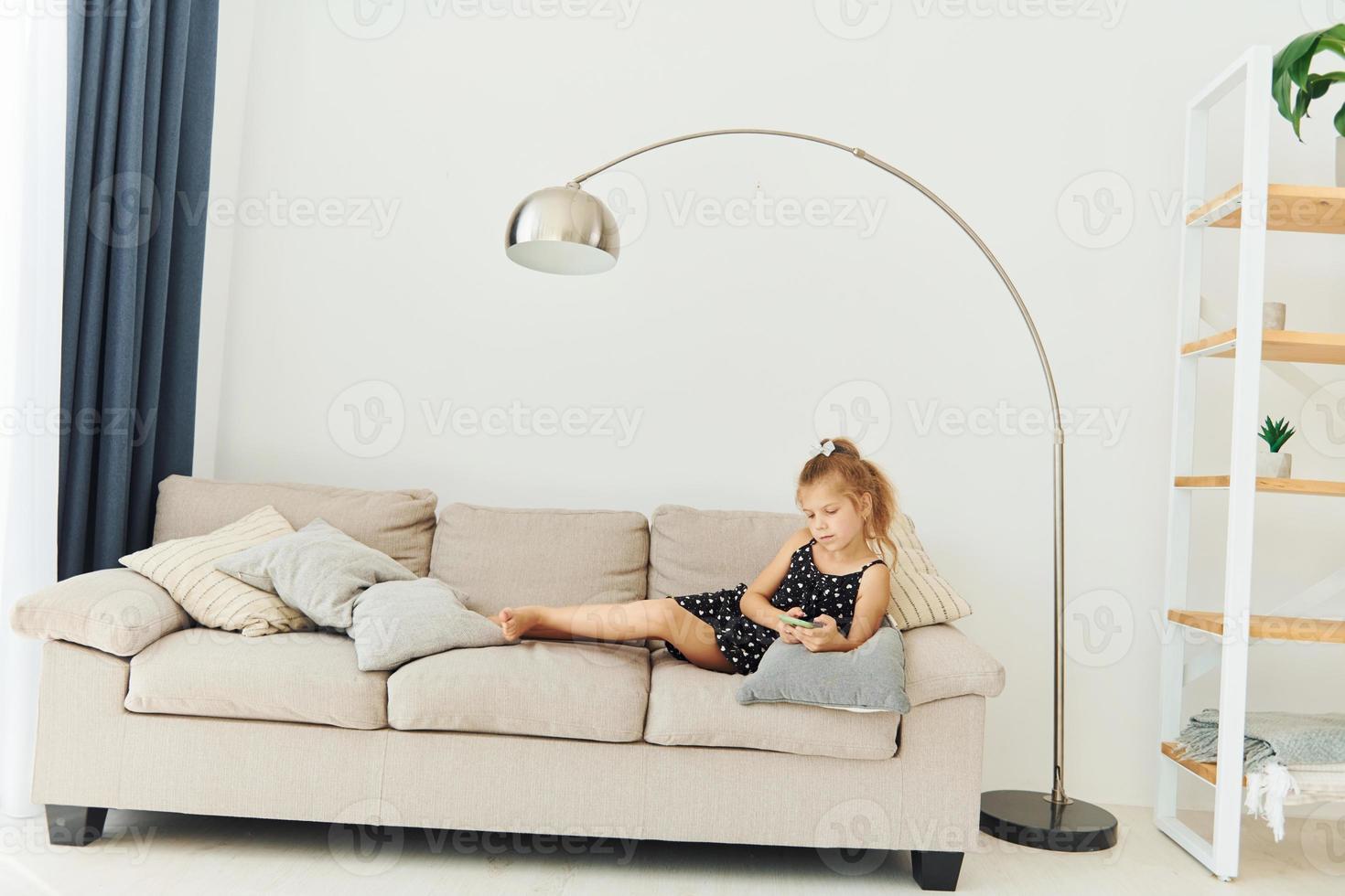 Little girl is laying down on the sofa with phone in hands 15420970 Stock Photo at Vecteezy