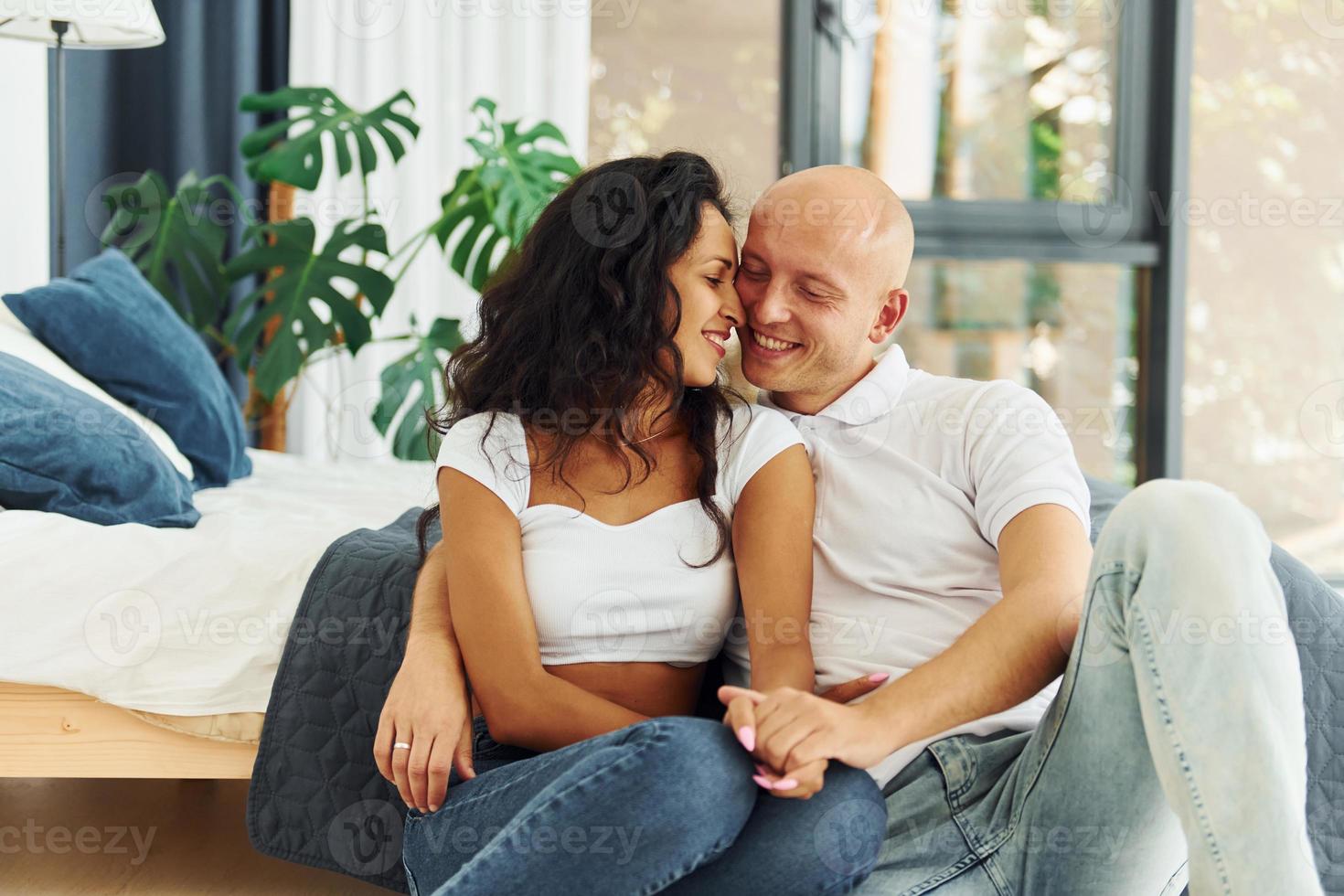 Sitting and embracing each other. Cheerful couple is together indoors photo