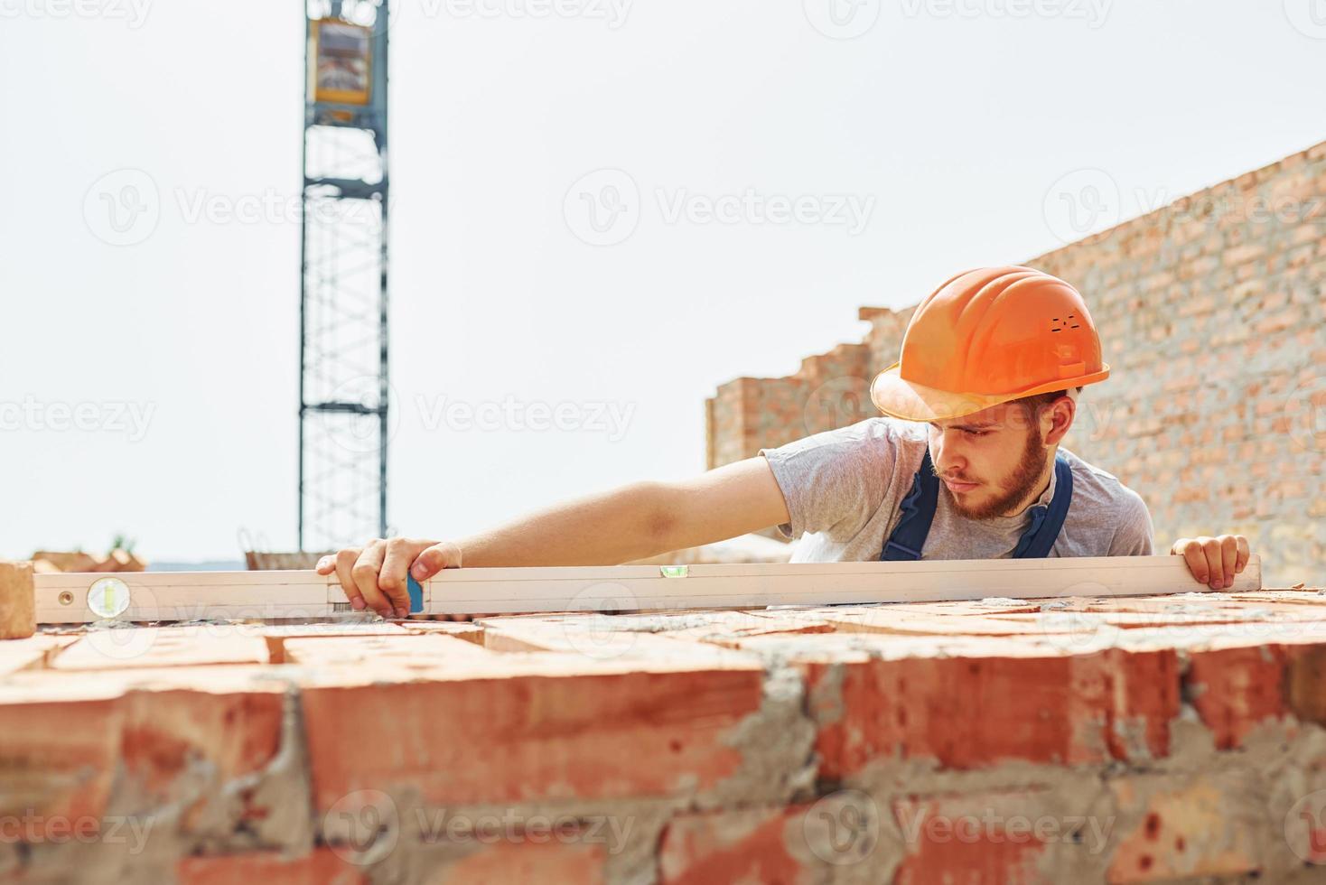 Busy day. Young construction worker in uniform is busy at the unfinished building photo