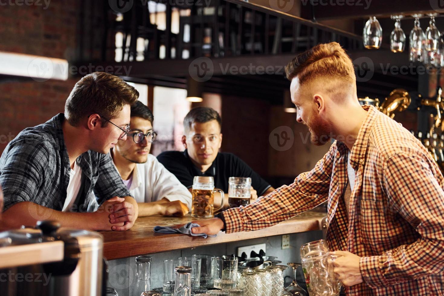 jóvenes alegres con ropa informal sentados en el pub foto