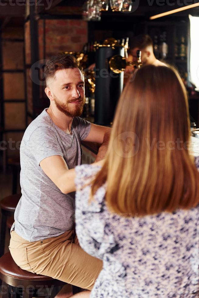 hablando unos con otros. gente con ropa informal sentada en el pub foto