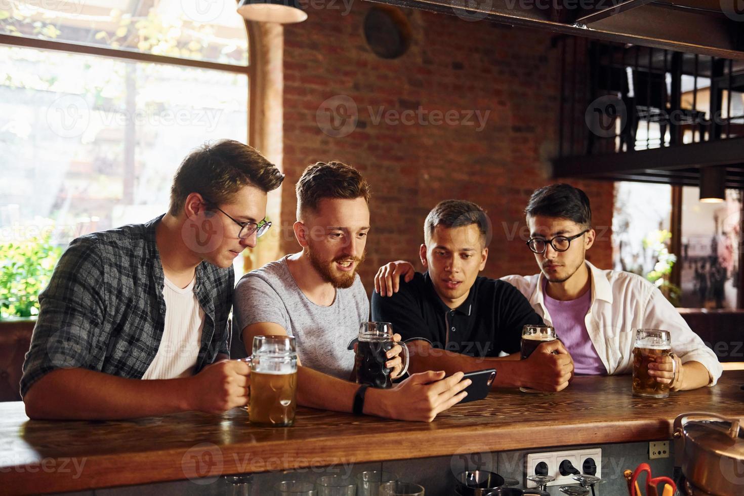 By the table. People in casual clothes sitting in the pub photo