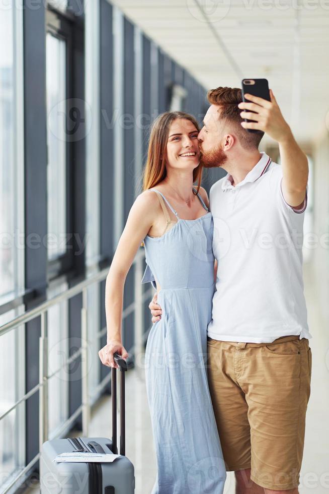 Happy couple. Young traveler is on the entrance hall in the airport photo