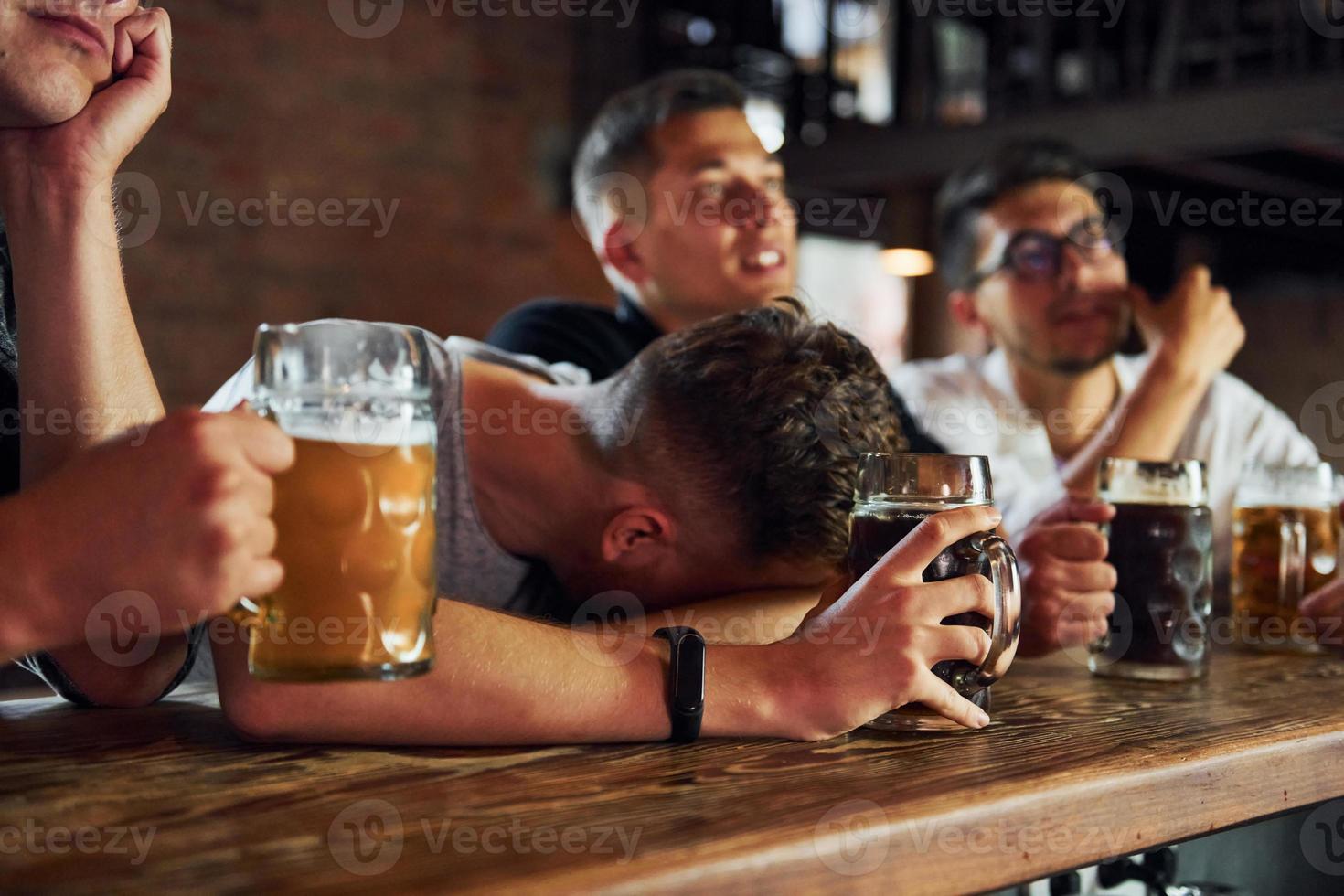 Side view of friends with beer. People in casual clothes sitting in the pub photo