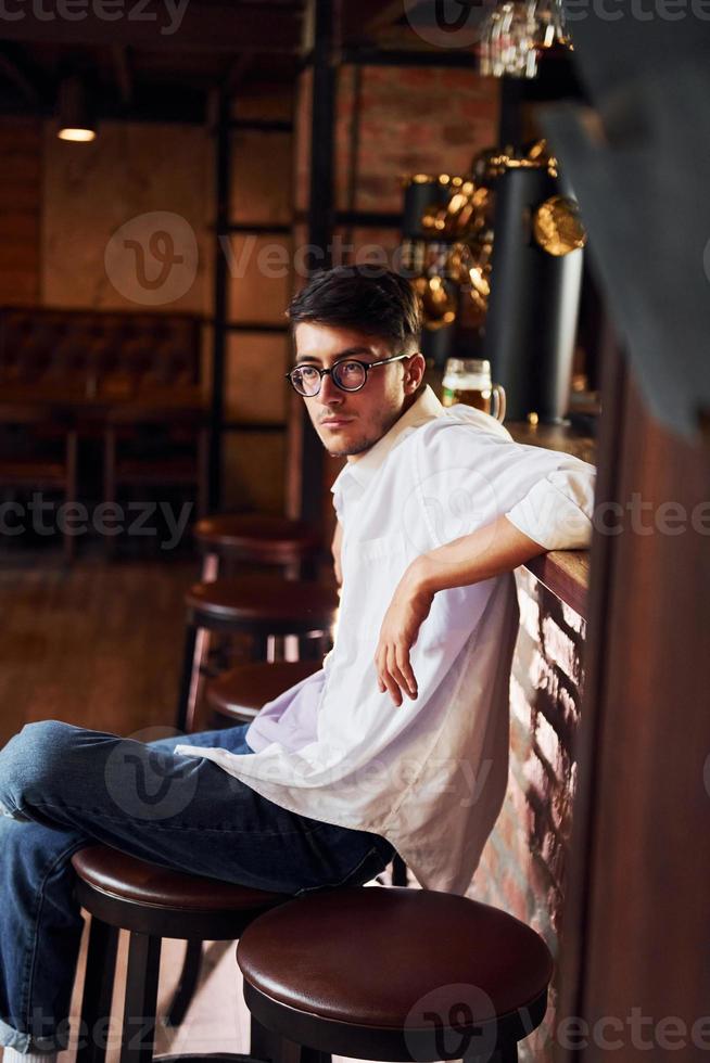 en la silla. hombre con ropa informal sentado en el pub foto