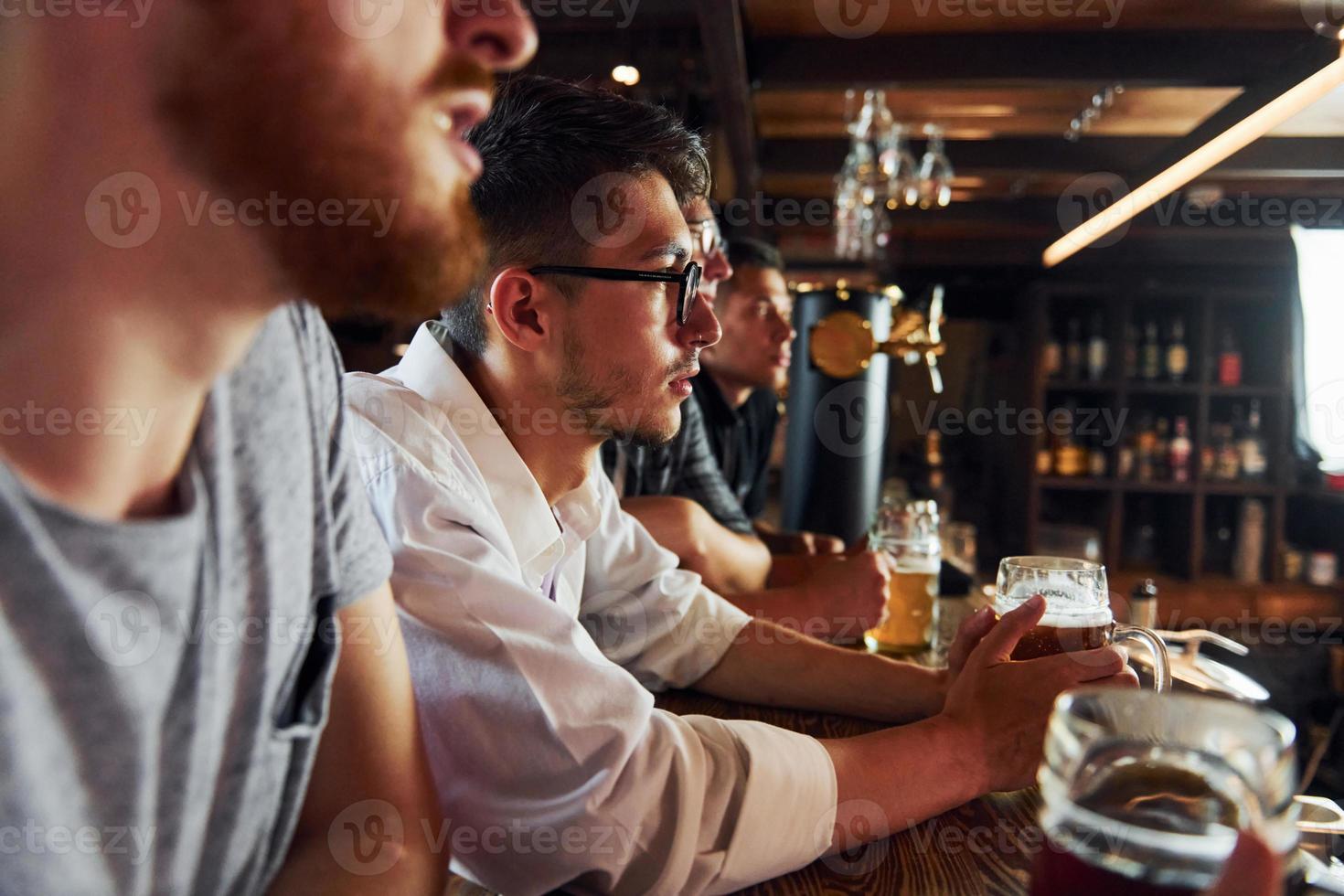By the table. People in casual clothes sitting in the pub photo