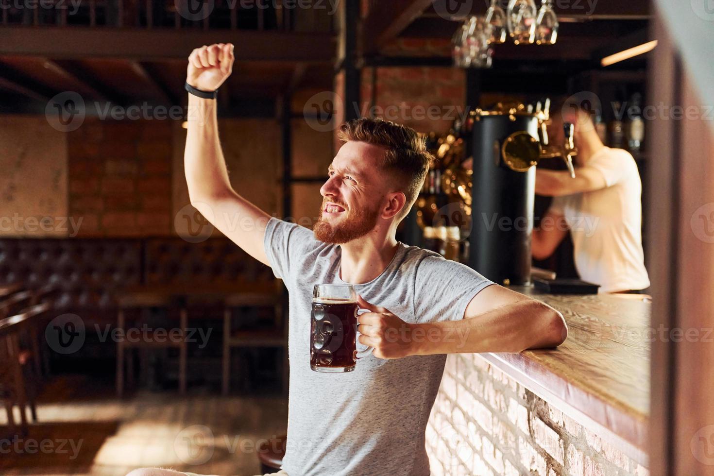 With beer. Man in casual clothes sitting in the pub photo