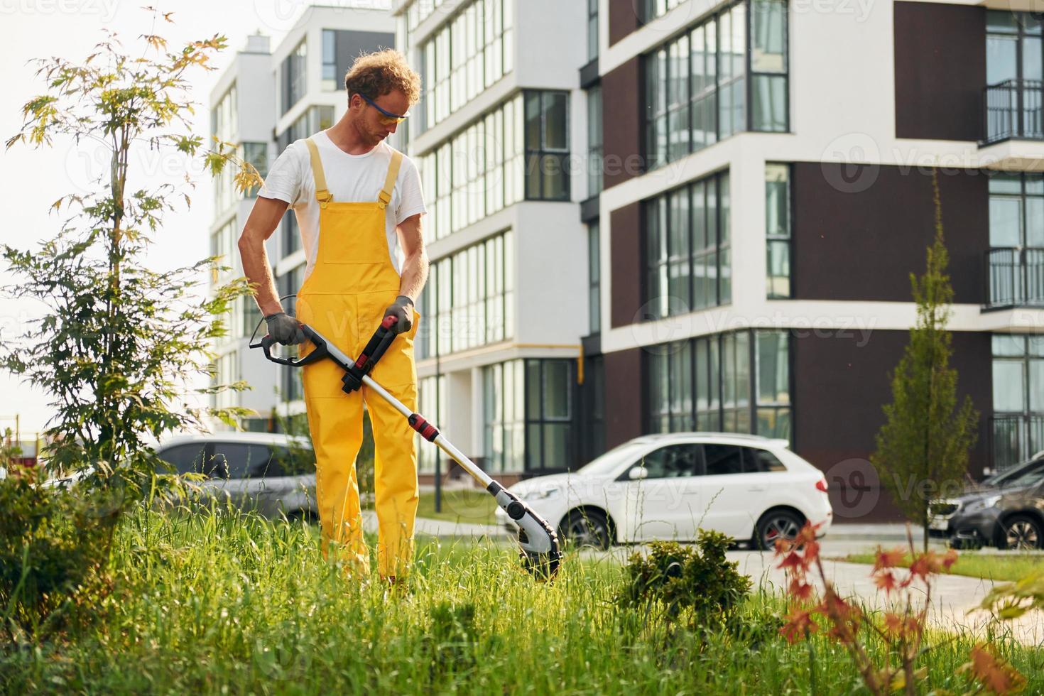 One person. Man cut the grass with lawn mover outdoors in the yard photo
