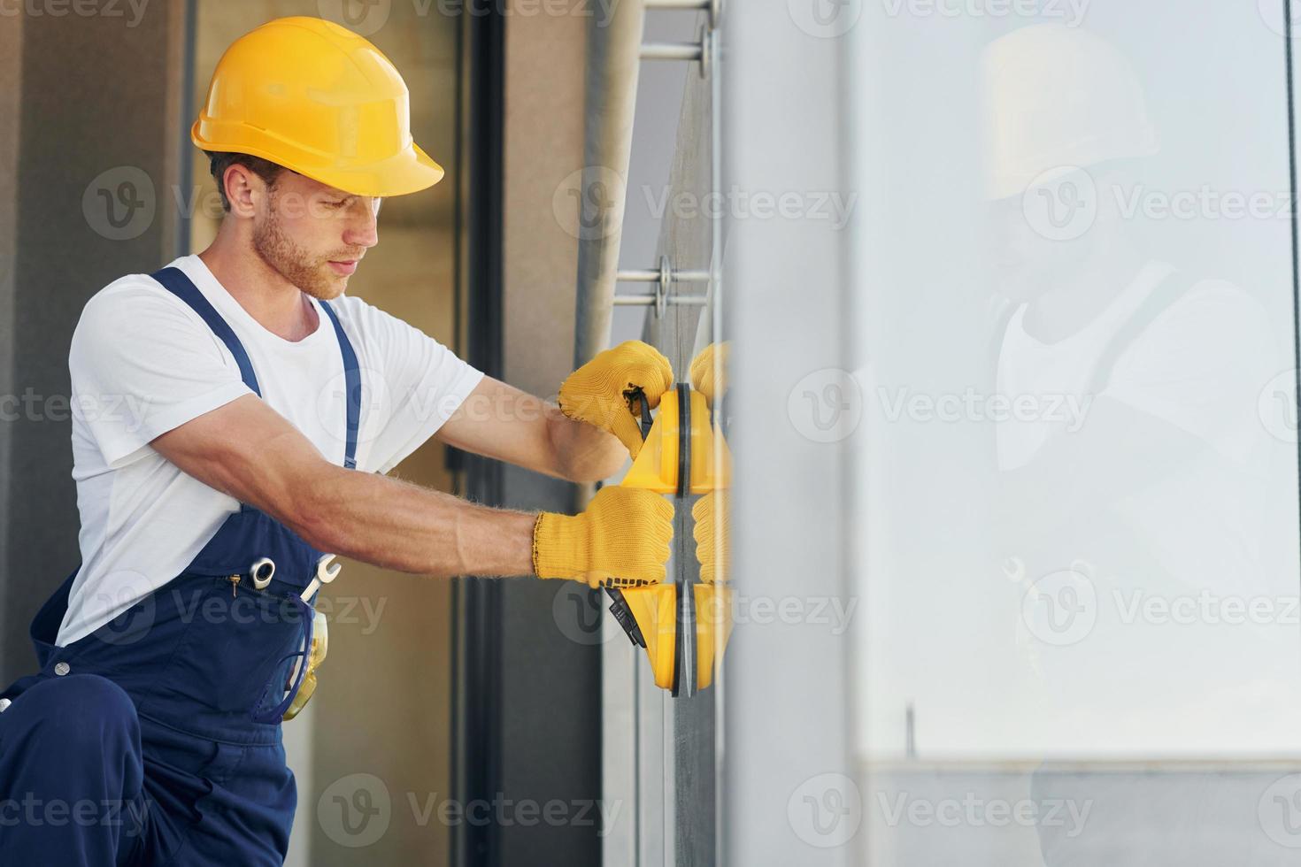 Side view. Young man working in uniform at construction at daytime photo