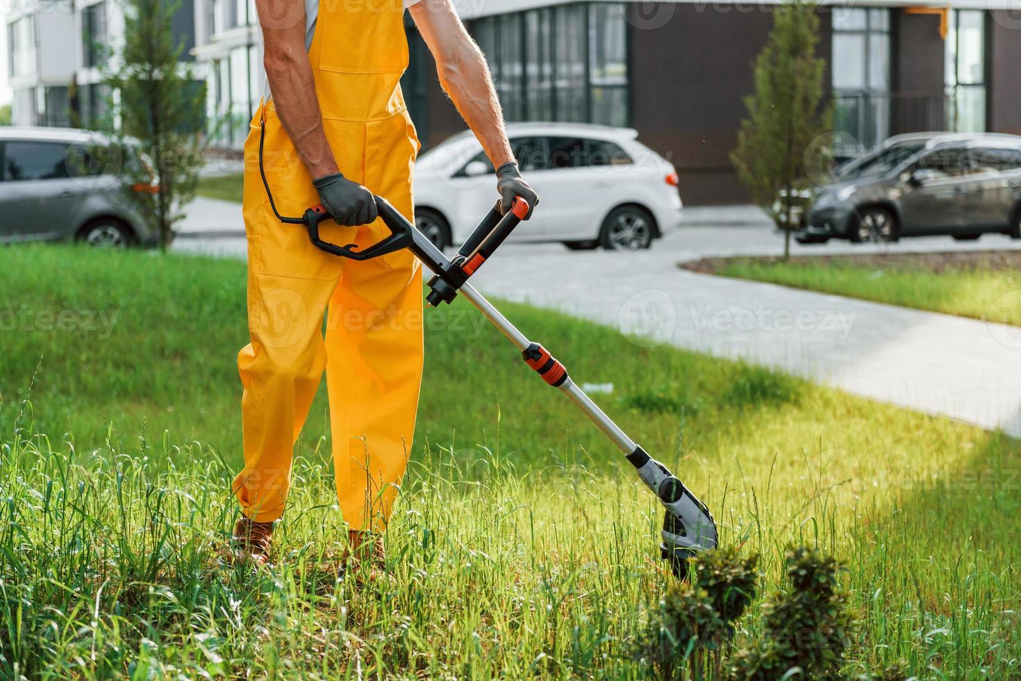 Building exterior at background. Man cut the grass with lawn mover outdoors in the yard photo