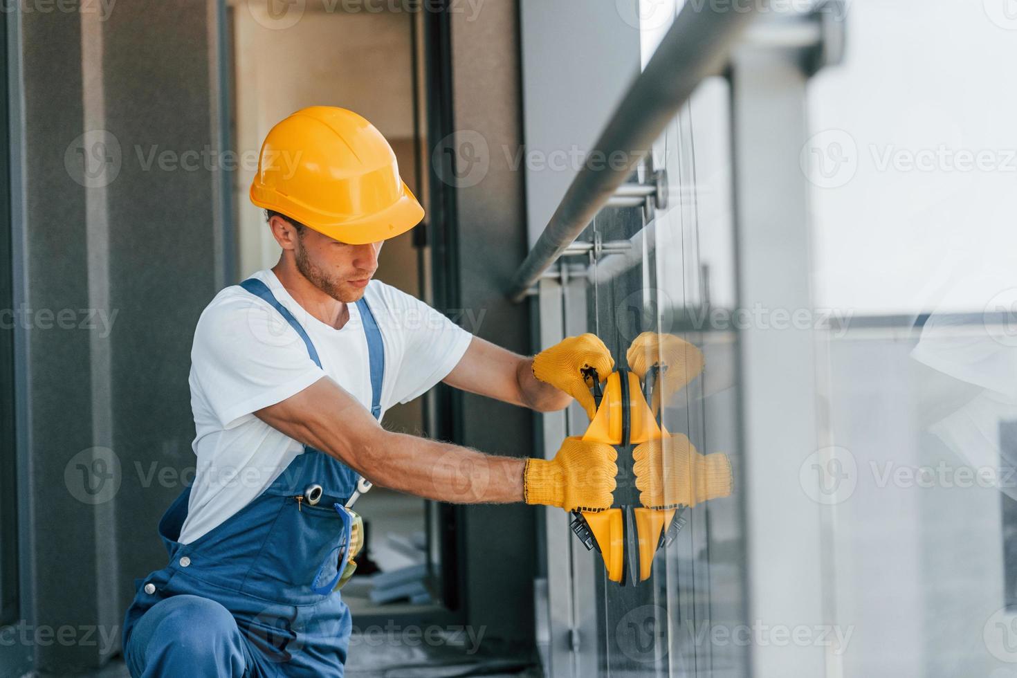 Installation of windows. Young man working in uniform at construction at daytime photo