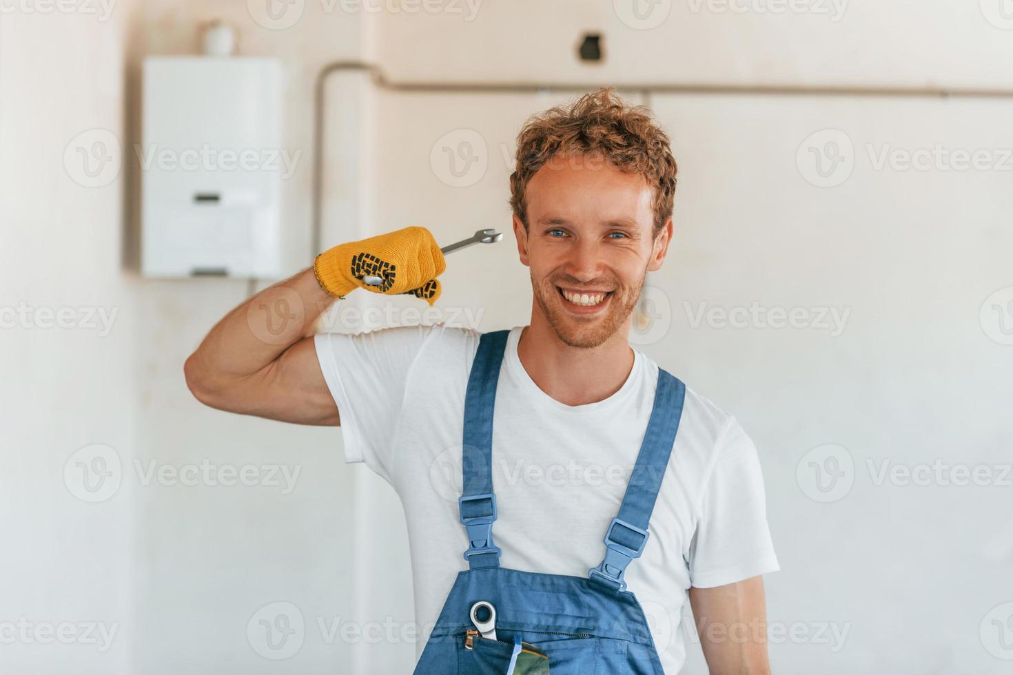 Professional occupation. Young man working in uniform at construction at daytime photo