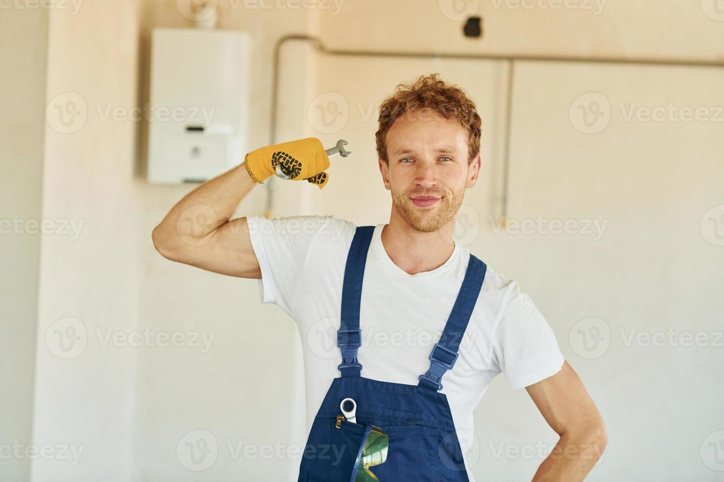 Professional occupation. Young man working in uniform at construction at daytime photo