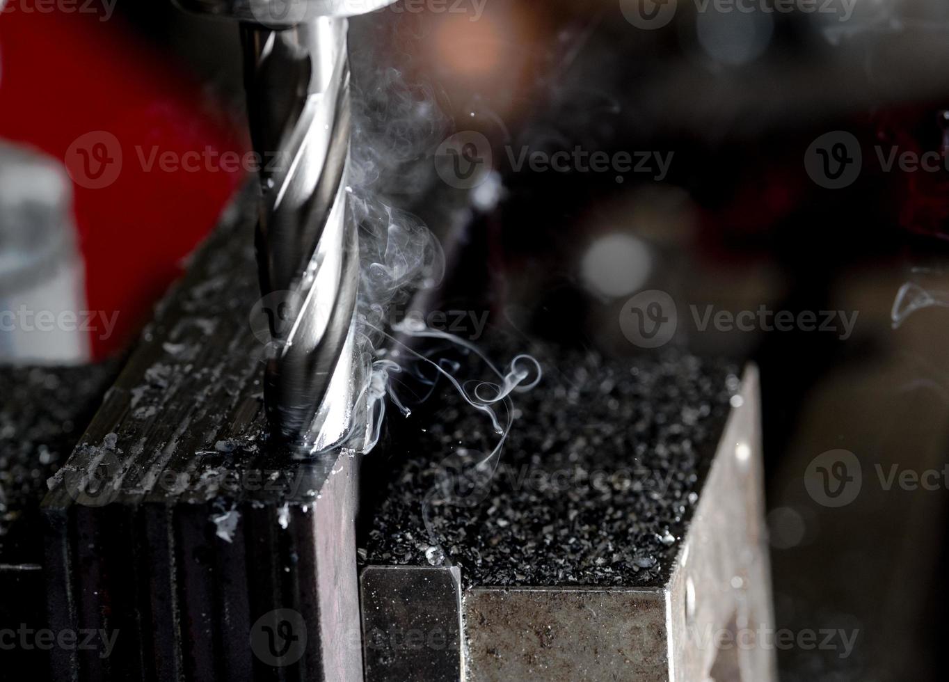 Bridgeport CNC end mill finishing a stack of steel plate with metal filings chips and light smoke photo