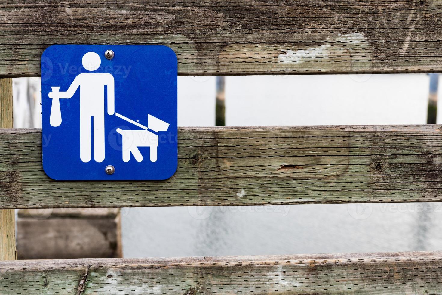 Poop scoop sign on a wooden rail fence photo