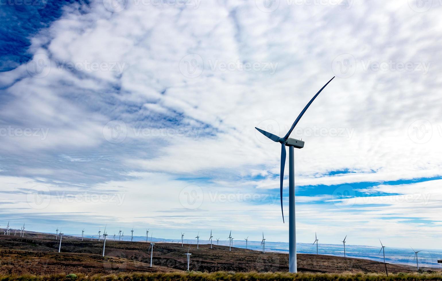 Green sustainable energy windmill power turbine electricity generators on rolling hills with clouds and blue sky photo
