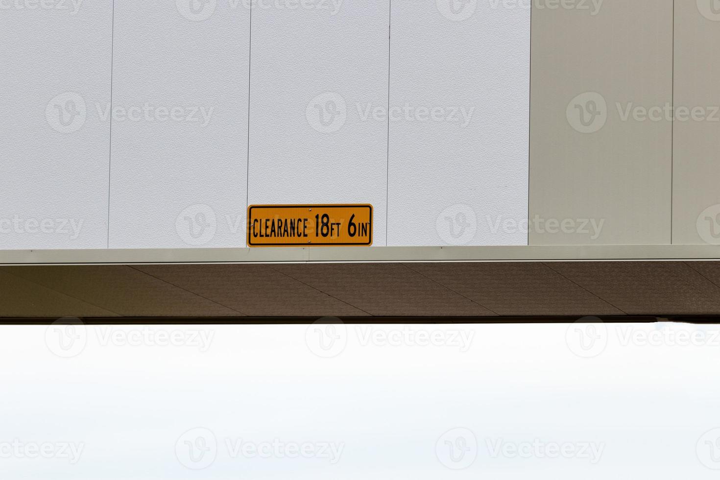 Low clearance sign on a white overpass photo