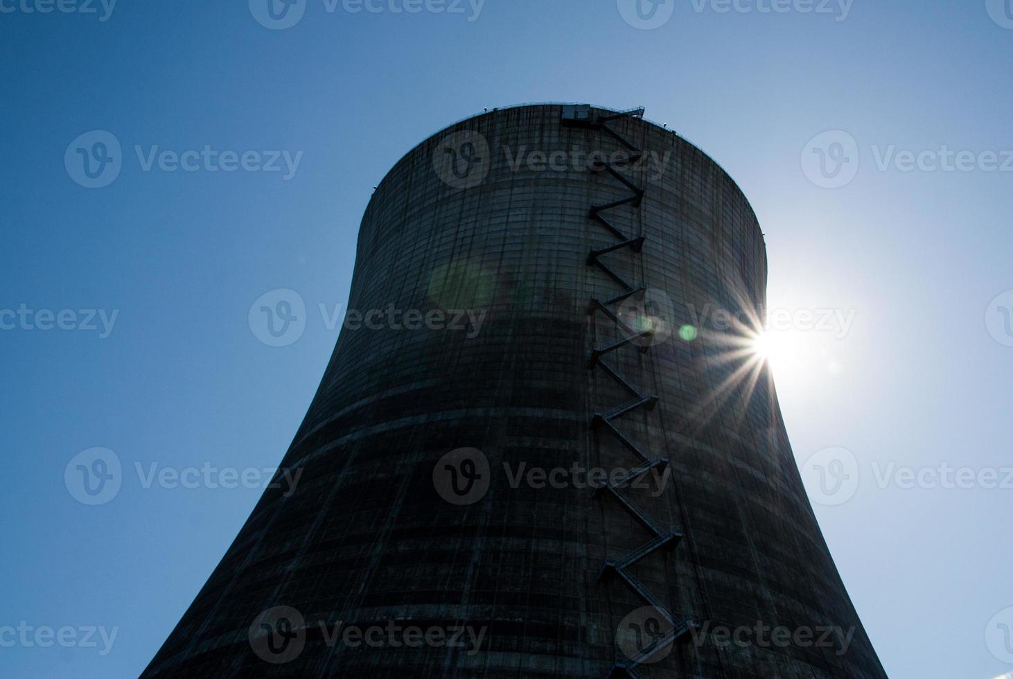 Nuclear cooling tower under a blue sky with a sunburst photo