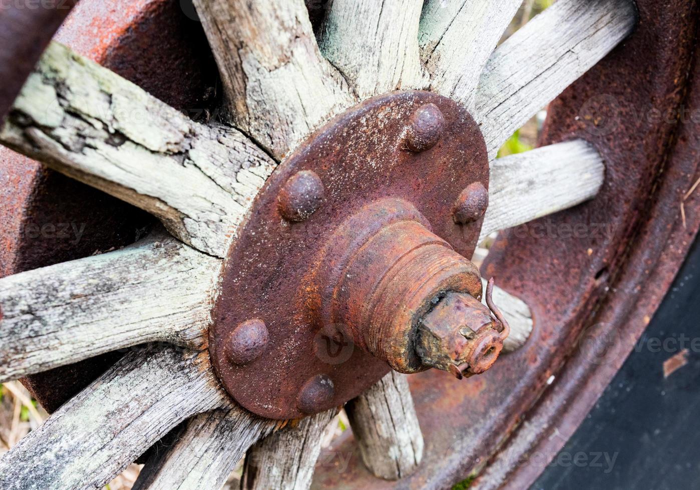 Vintage antique automotive tractor wood wheel spokes and hub covered in rust and oxidation photo