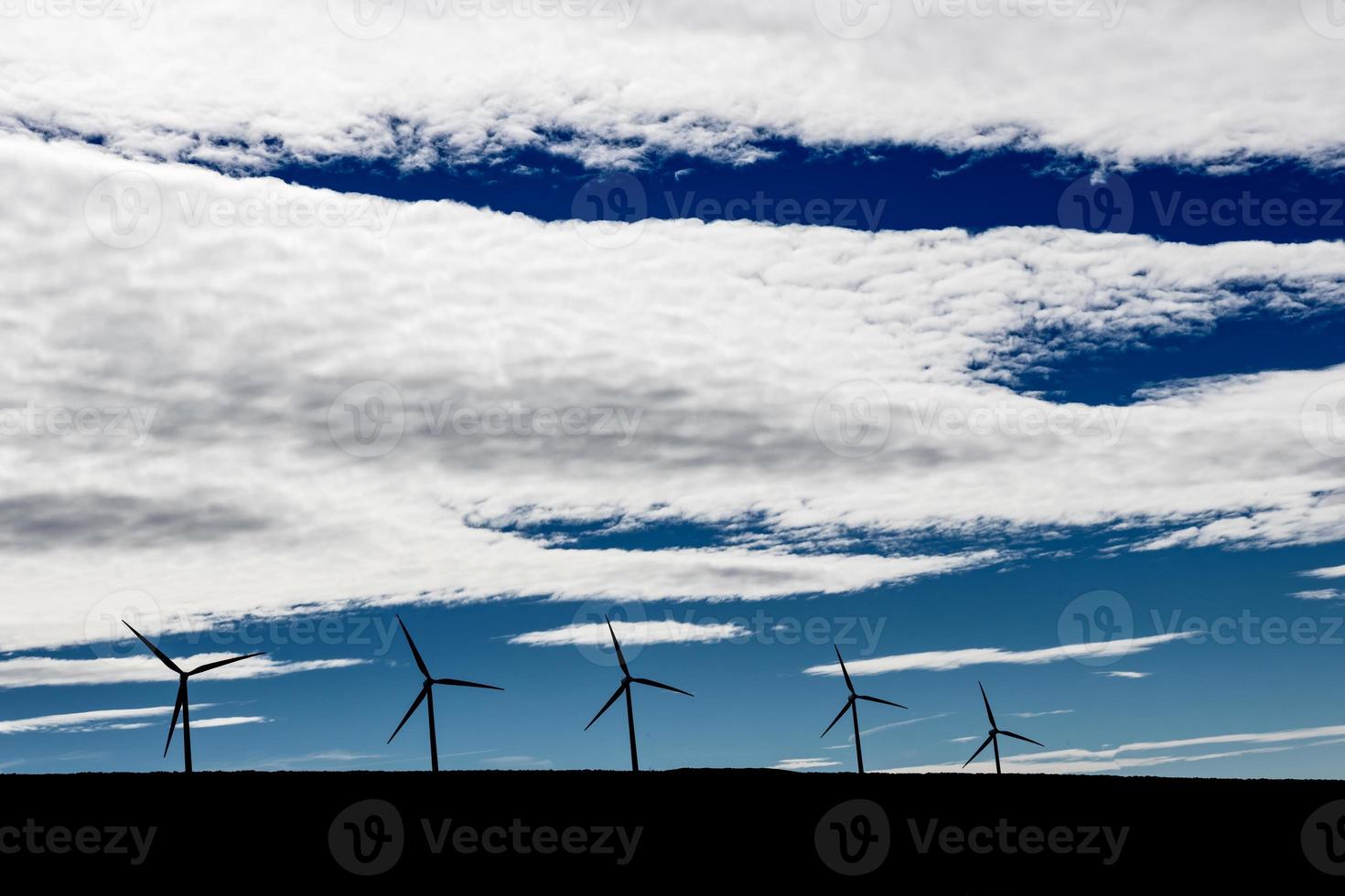 Green sustainable energy windmill power turbine electricity generators on rolling hills with clouds and blue sky photo