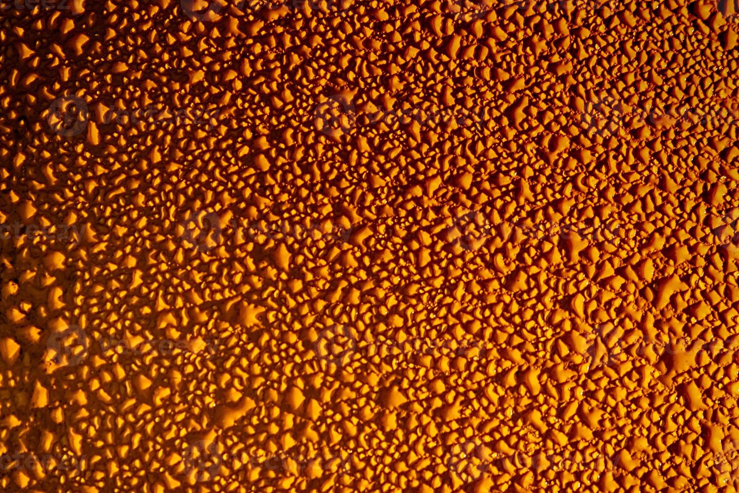 Glistening rain drops on an orange metal sheet photo