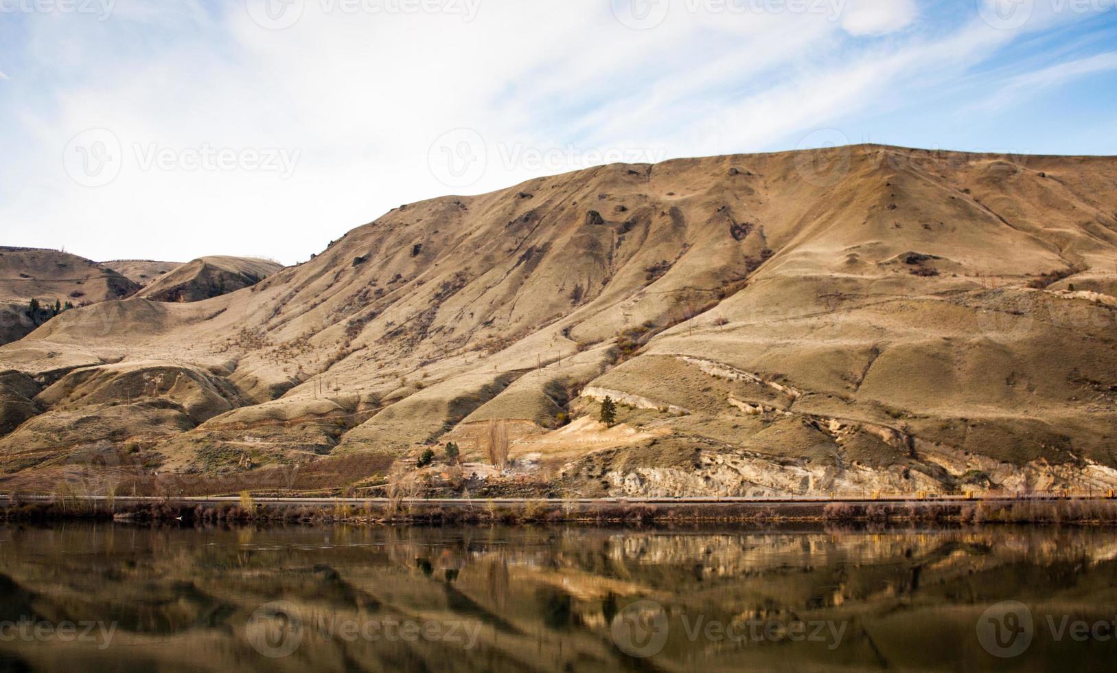 Golden desert canyon with reflection in river beneath photo