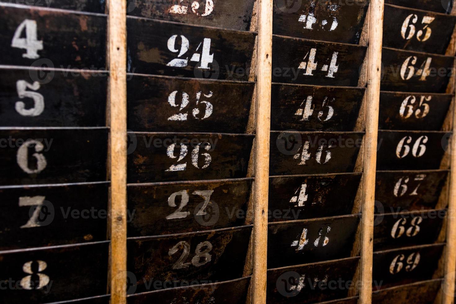 Numbered old and faded time clock punch card wall rack photo