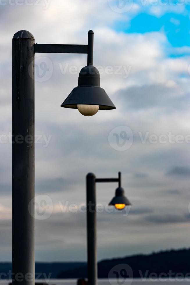 Street lamp posts illuminated against a blue sky photo