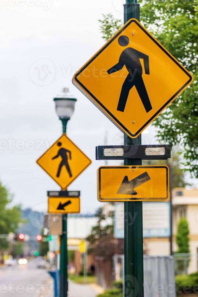Crosswalk signs on a lamp post with arrows and a man symbol photo
