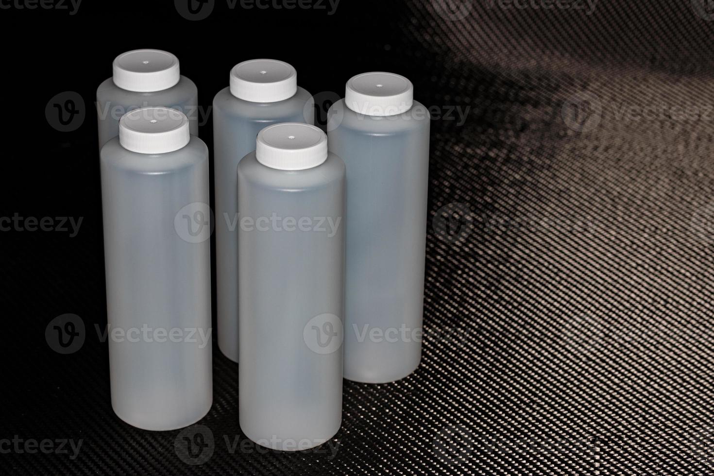 White plastic containers with lids on carbon fiber photo