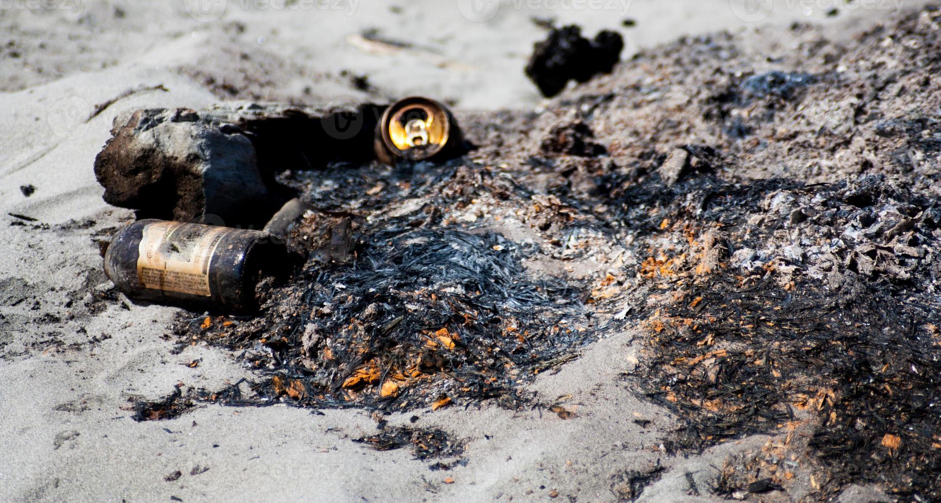 Garbage on a beach camp fire left over from a party photo