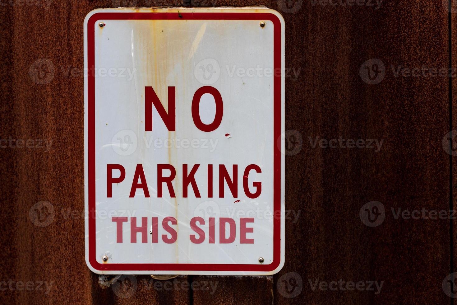 Old faded worn metal no parking this side sign photo